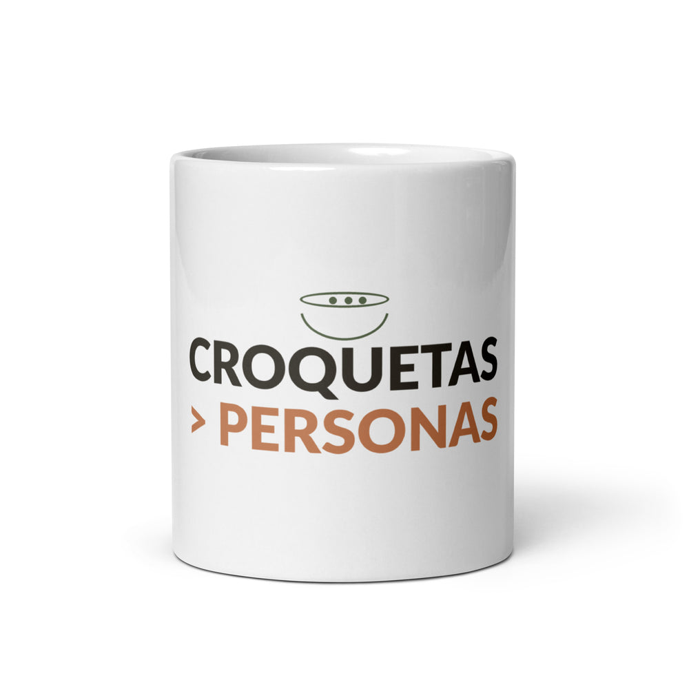 Taza blanca de cerámica con el lema «Croquetas > Personas», vista frontal